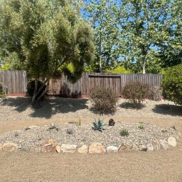 side yard converted to a succulent garden raised planter bed with boulders around the edge